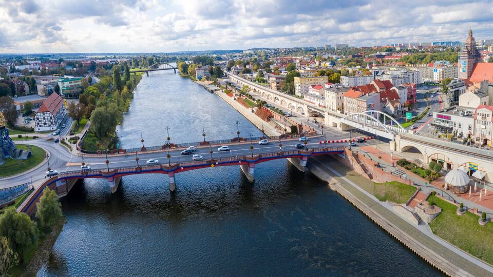 A river with a bridge, a roundabout, and a cityscape with historic buildings.