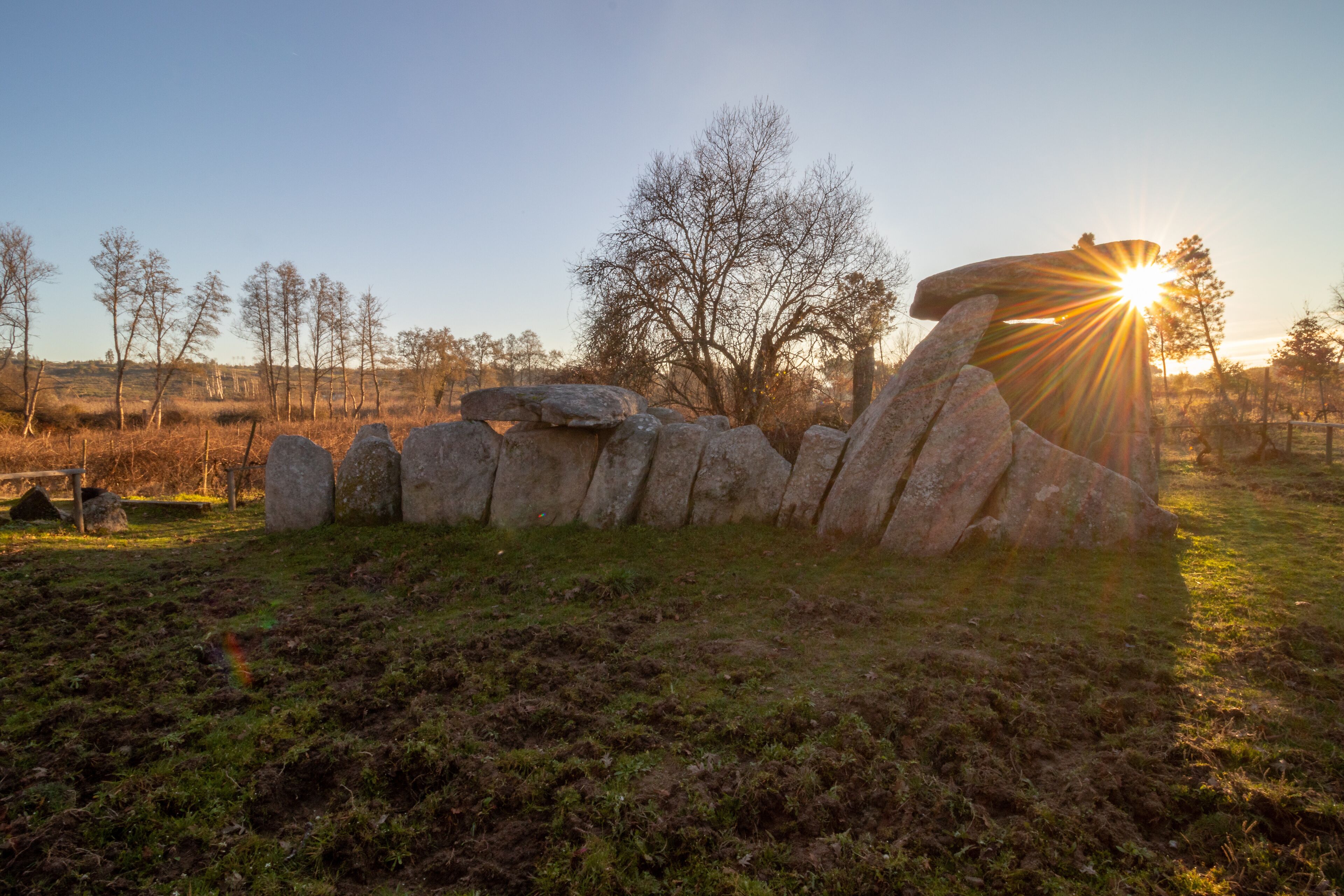 A stone circle with the sun setting behind it.