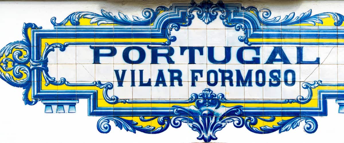 A Portuguese street sign with ornate blue and yellow tiles.