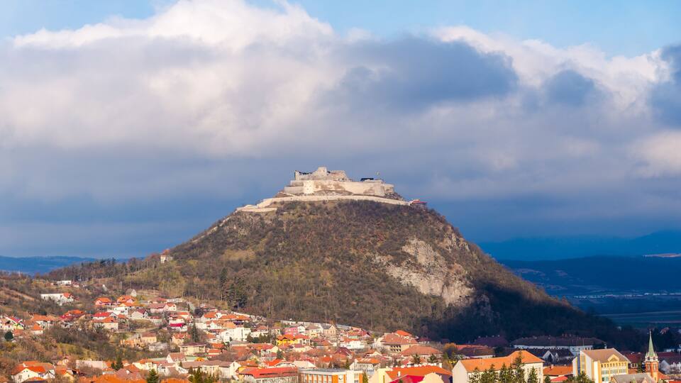 A town with a prominent castle on a hill, surrounded by colorful houses and a clear sky.