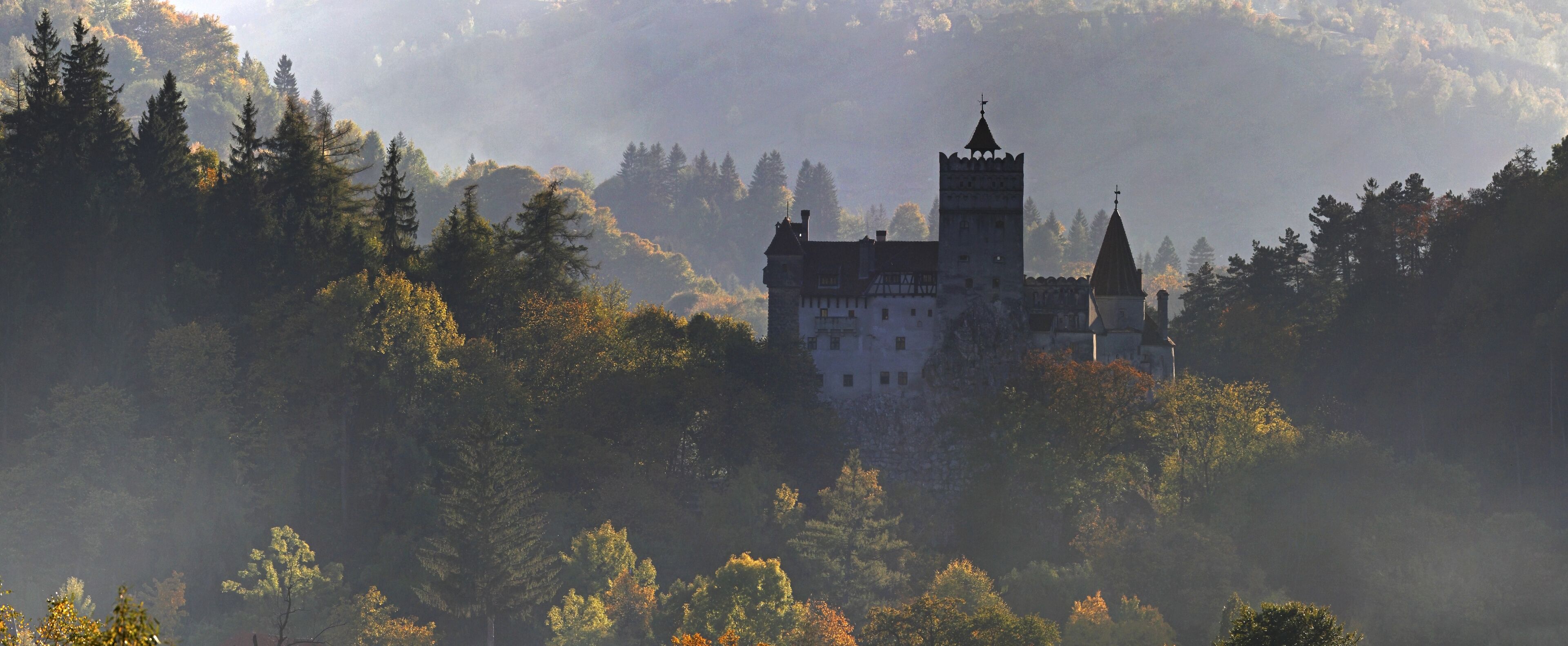A castle surrounded by forested hills.