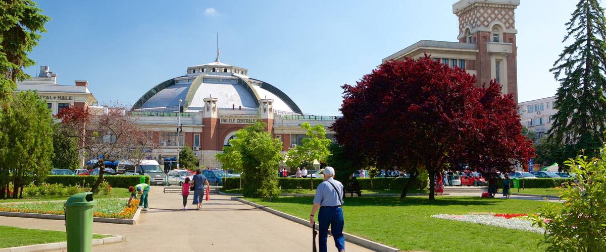 A park with a large dome building, a clock tower, and people walking.