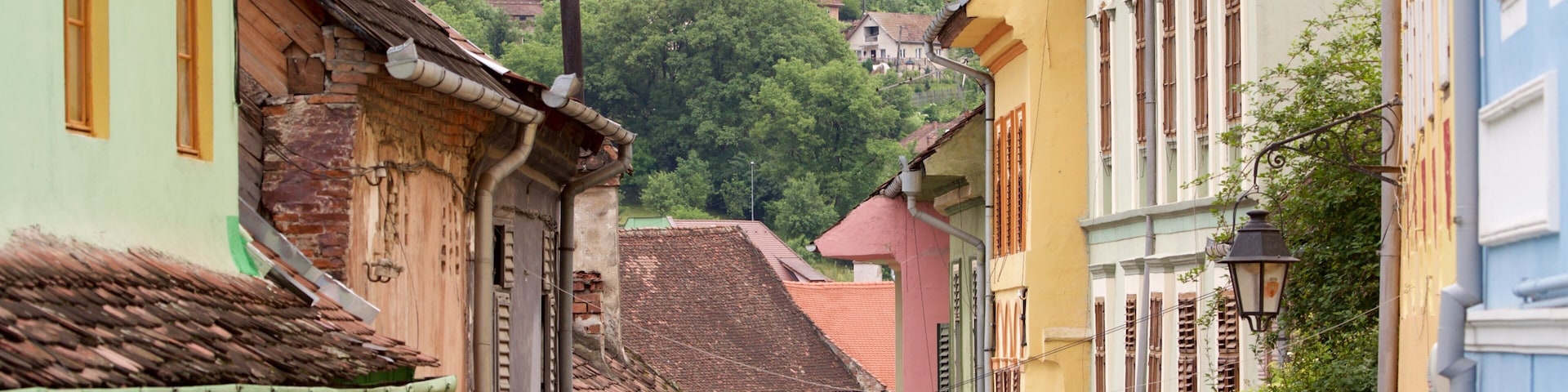 Una calle estrecha con edificios coloridos, un letrero que dice 'ARTIZAMAT CERAMICA' y una colina con casas al fondo.