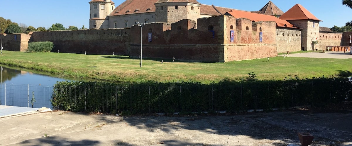 A historic castle with a moat, a tower, and a well-maintained lawn.
