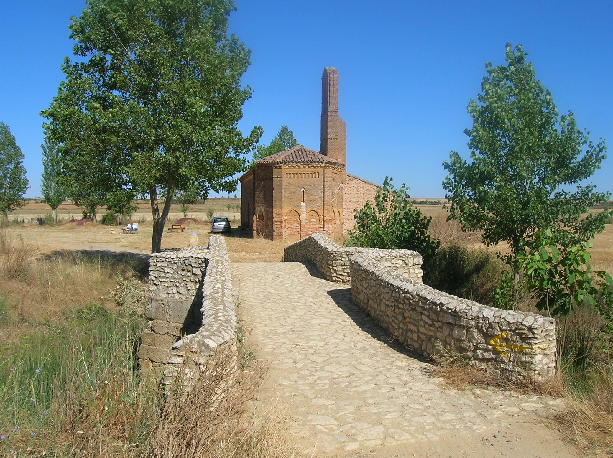 Se encuentra a unos tres kilómetros al este de Sahagún. Es la primera edificación que encontramos en el Camino francés al entrar en la provincia de León. Al estar junto al puente sobre el río Valderaduey fue lo que le dio el nombre con que se conoce. De estilo mudéjar, posee una sola nave y una cabecera muy pequeña con un ábside en semihexágono, arquerías ciegas y frisos de esquina. Durante algún siglo la ermita y hospital de Nuestra Señora del Puente lo administraron los Canónigos Regulares de Trianos. Desde el siglo XVI, figura el Cabildo de curas de Sahagún como sucesores de la Cofradía y administradores del conjunto. Vuela hasta esta localización. Necesitas el programa Google Earth. Esta foto participó en el juego En un lugar de Flickr.