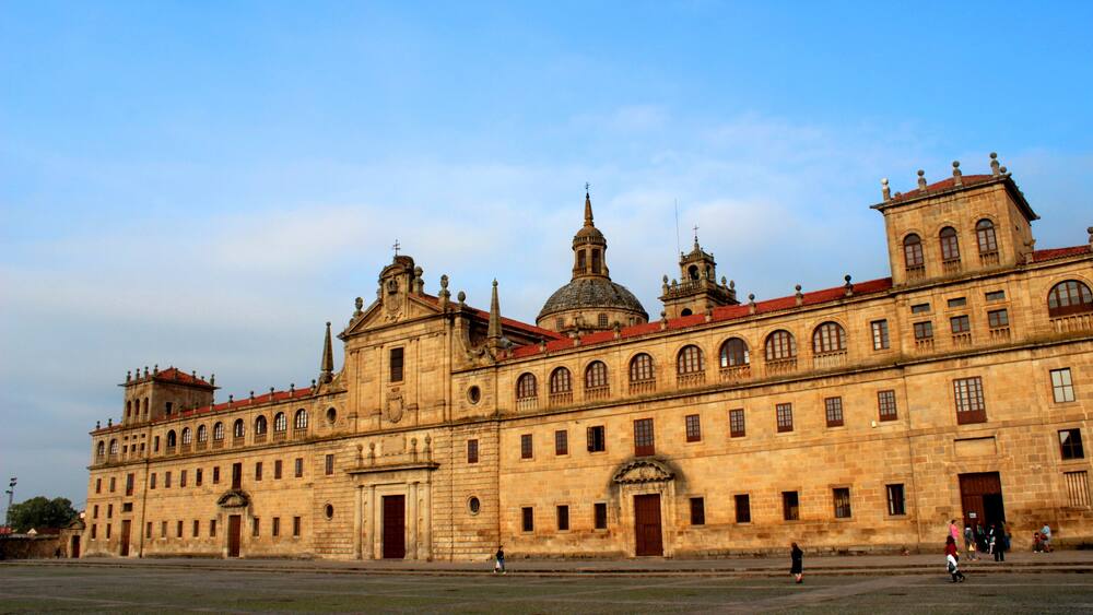 Un vaste bâtiment historique doté de plusieurs dômes et de tours, d’une cour intérieure et surplombé d’un ciel d’un bleu éclatant.