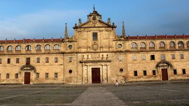 A large historic building with a central entrance, multiple windows, and a red-tiled roof.
