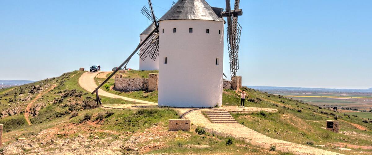 A white windmill on a hill with a clear sky.