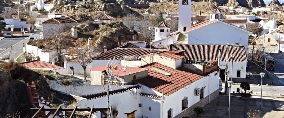 A town with white buildings, red-tiled roofs, and a prominent church with a bell tower.