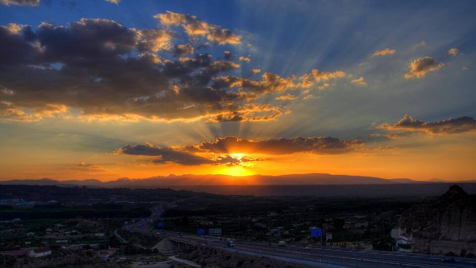 A sunset over a cityscape with mountains in the background.