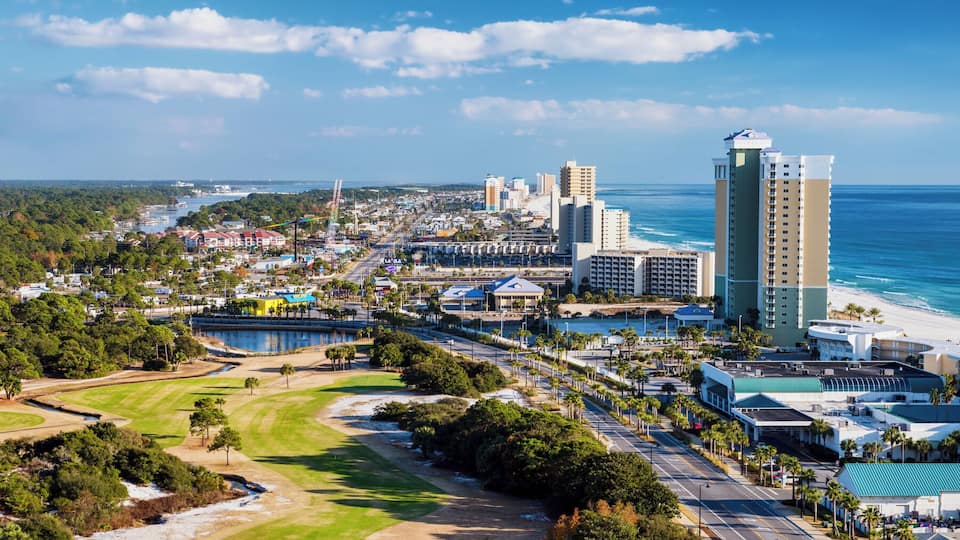 A coastal cityscape with a beach, golf course, and high-rise buildings.