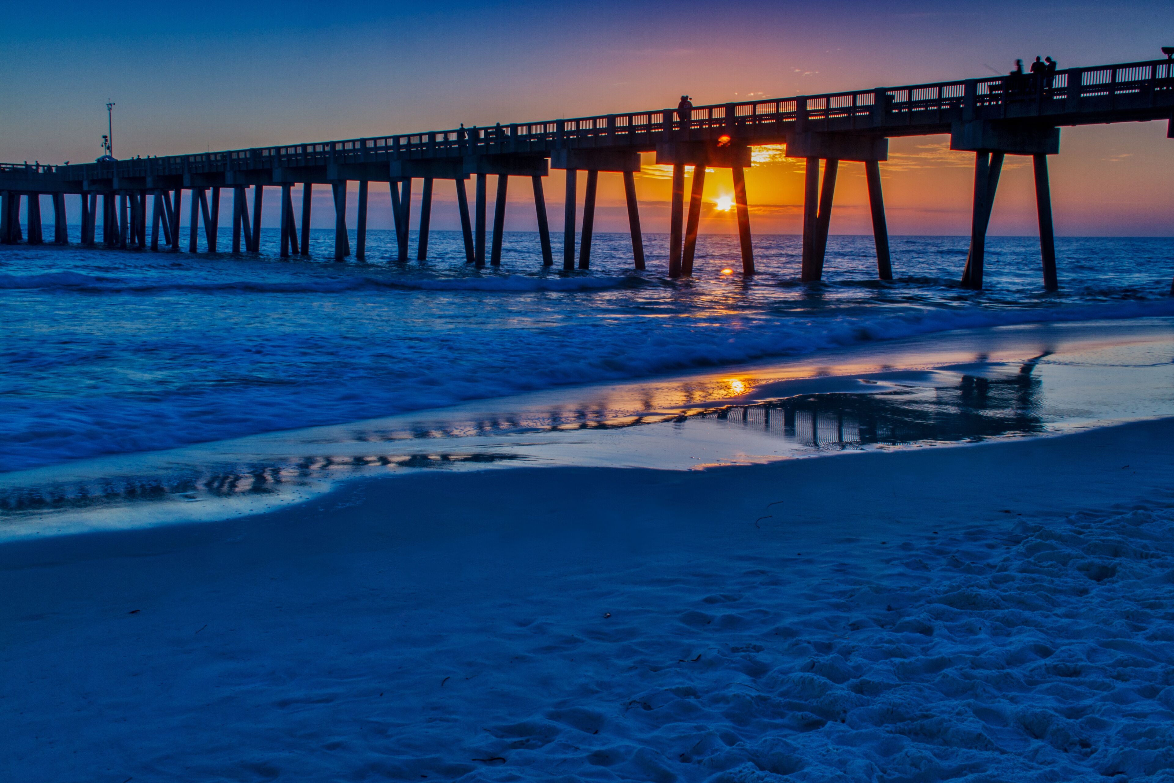 A pier extending into the ocean at sunset.