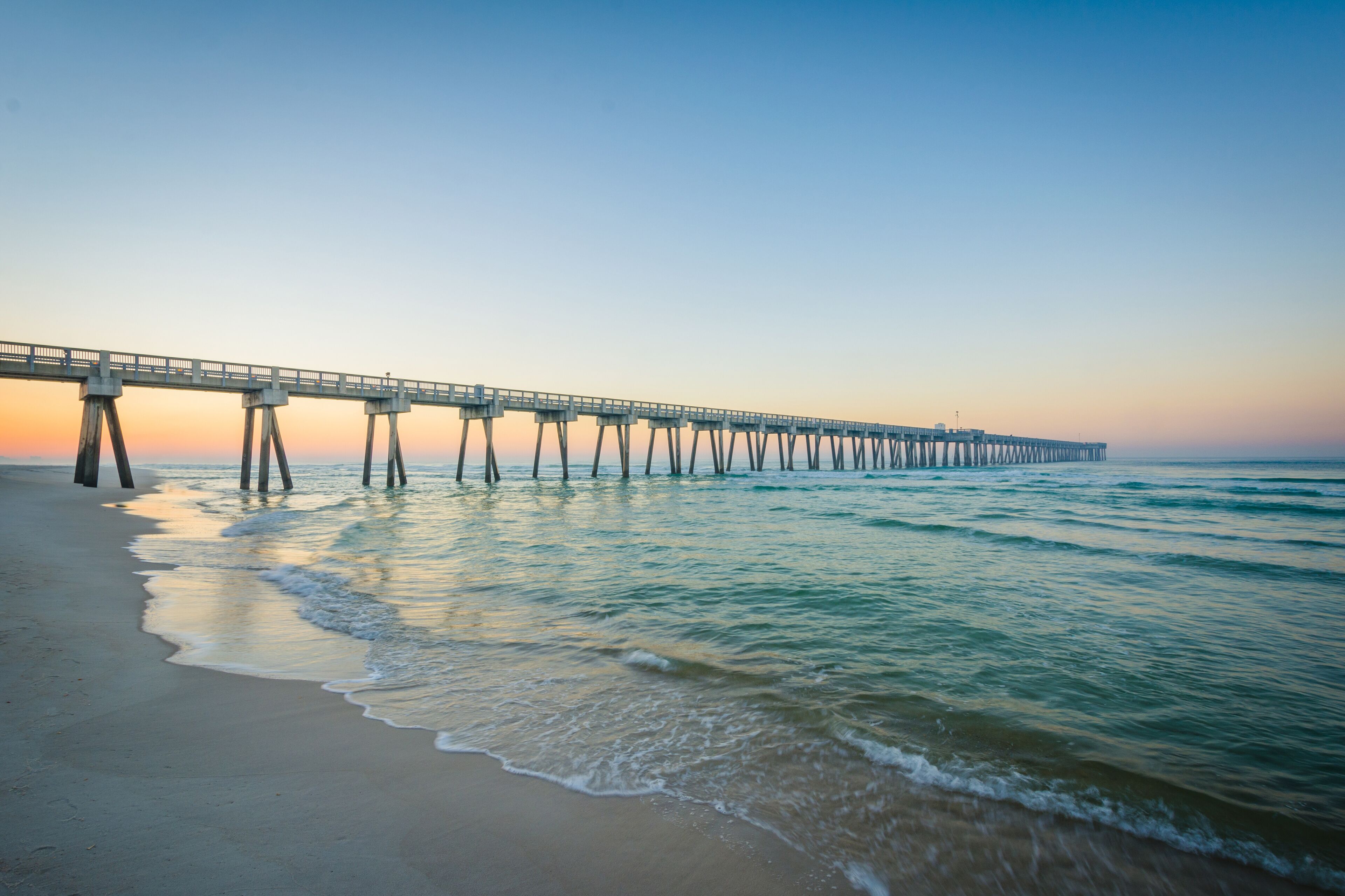 A pier extending into the ocean at sunset.
