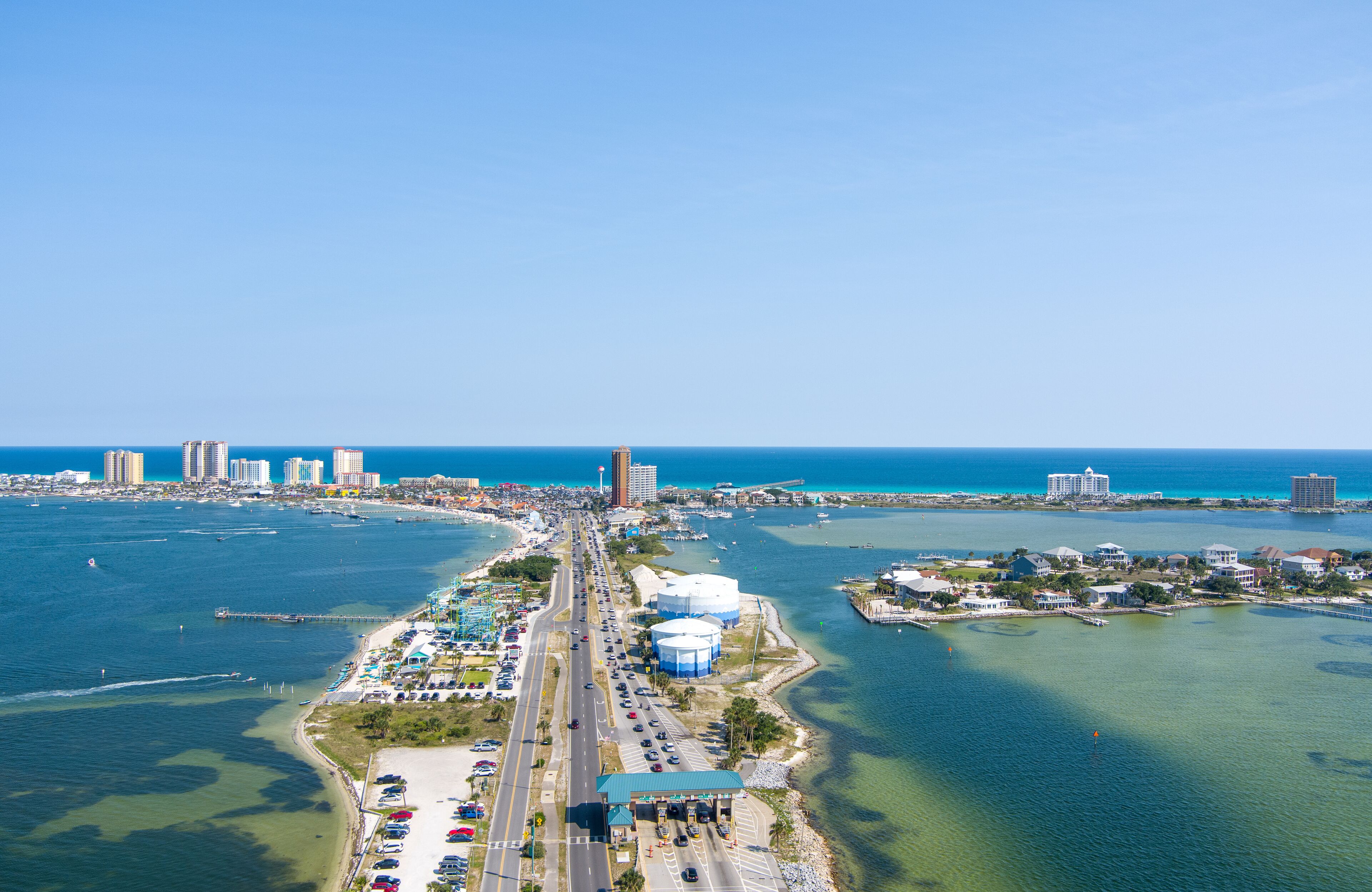 A coastal cityscape with a prominent bridge, marina, and high-rise buildings along the waterfront.