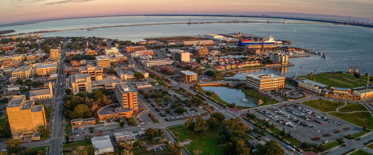 An aerial view of a coastal city with a prominent bridge, marina, and dense urban area.