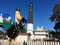 Un phare, une grande sculpture d’oiseau et une maison blanche avec un toit rouge.