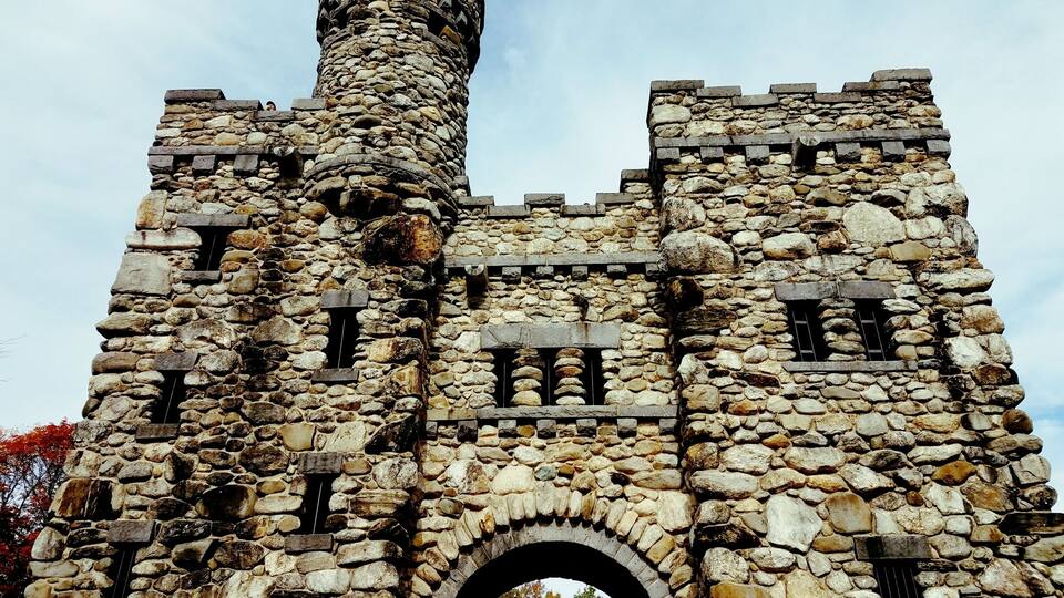 Eine steinerne Burg mit einem runden Turm und einem Rundbogenportal.