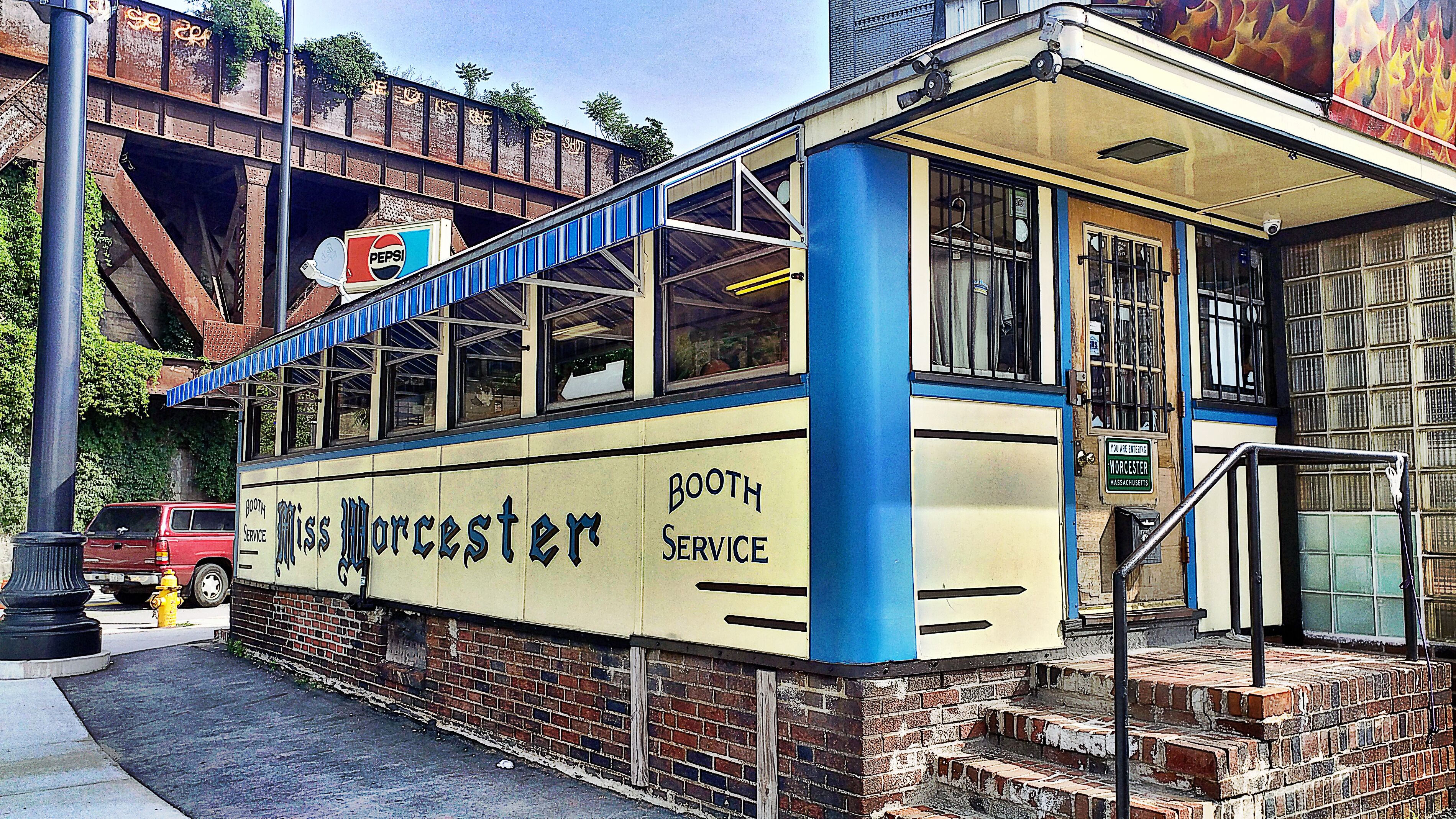 A vintage booth with 'Miss Worcester' and 'Booth Service' signage, located next to a red truck and a fire hydrant.