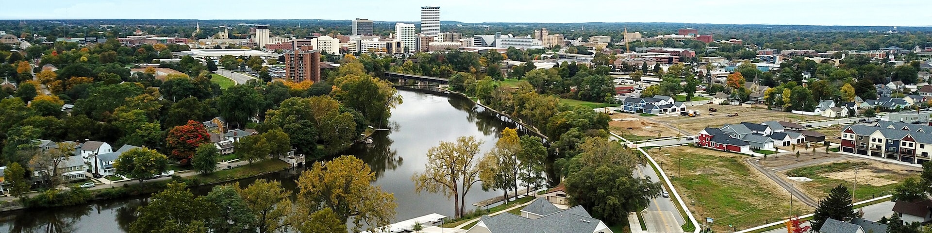 A river, residential houses, and a bridge in a suburban area.