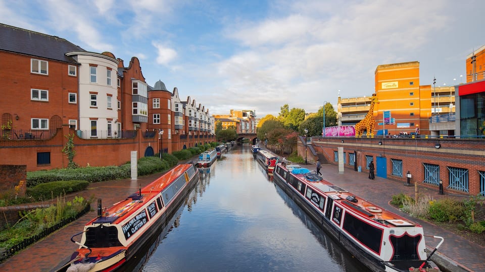 A canal with narrowboats, brick buildings, and a giraffe statue.