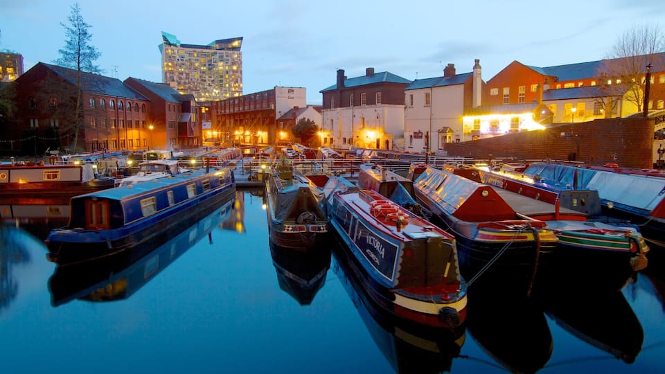 A marina with several narrowboats docked in calm water, surrounded by buildings and a modern high-rise in the background.