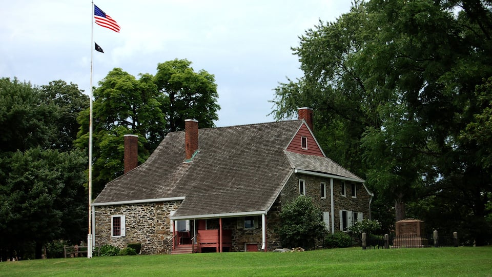 A stone house with a red roof and a flagpole with an American flag.