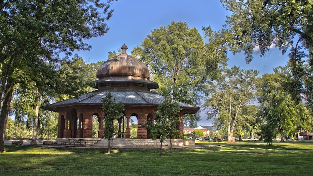 A historic building with a dome roof surrounded by trees in a park.