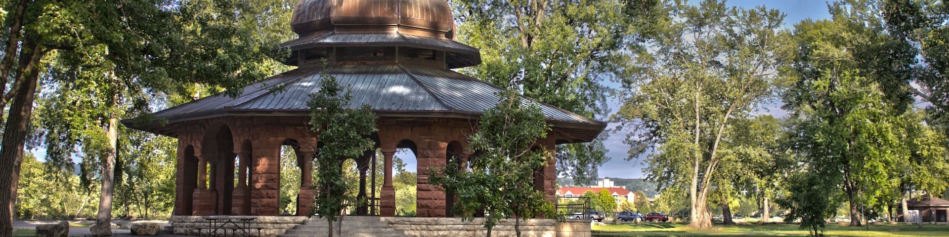 A historic building with a dome roof surrounded by trees in a park.