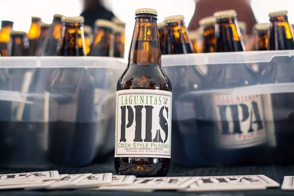 A bottle of Lagunitas Pils beer with other beer bottles in the background.