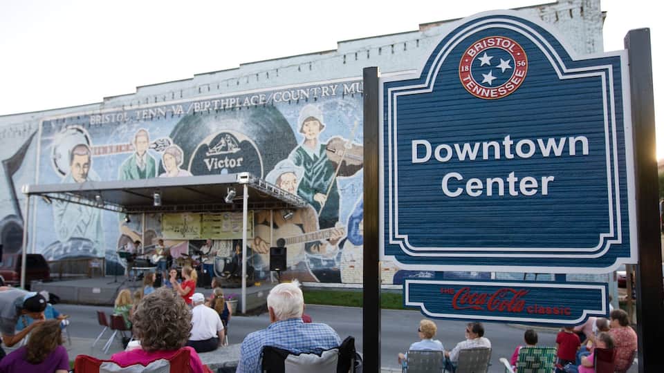A mural with musicians and the text "Victor". In front, there's a sign for the Downtown Center and a Coca-Cola Classic logo.