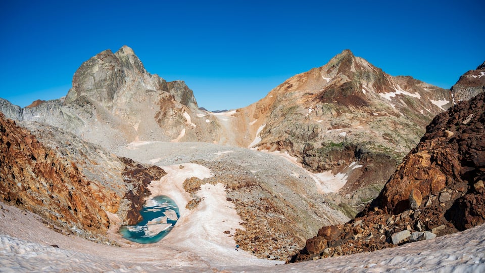 A glacier with a turquoise lake surrounded by rugged mountains.