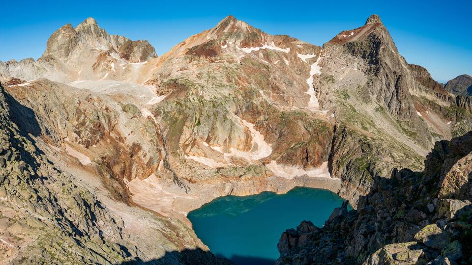 A mountain range with a clear blue lake nestled in a rocky valley.