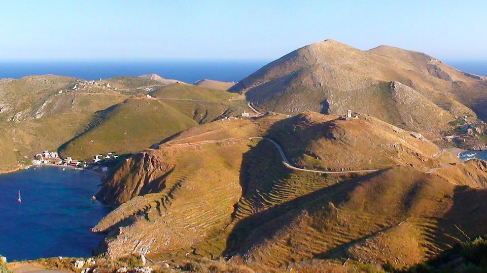 A mountainous island with a small settlement and a clear view of the surrounding sea.