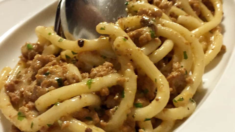 A plate of spaghetti with meat sauce and herbs.