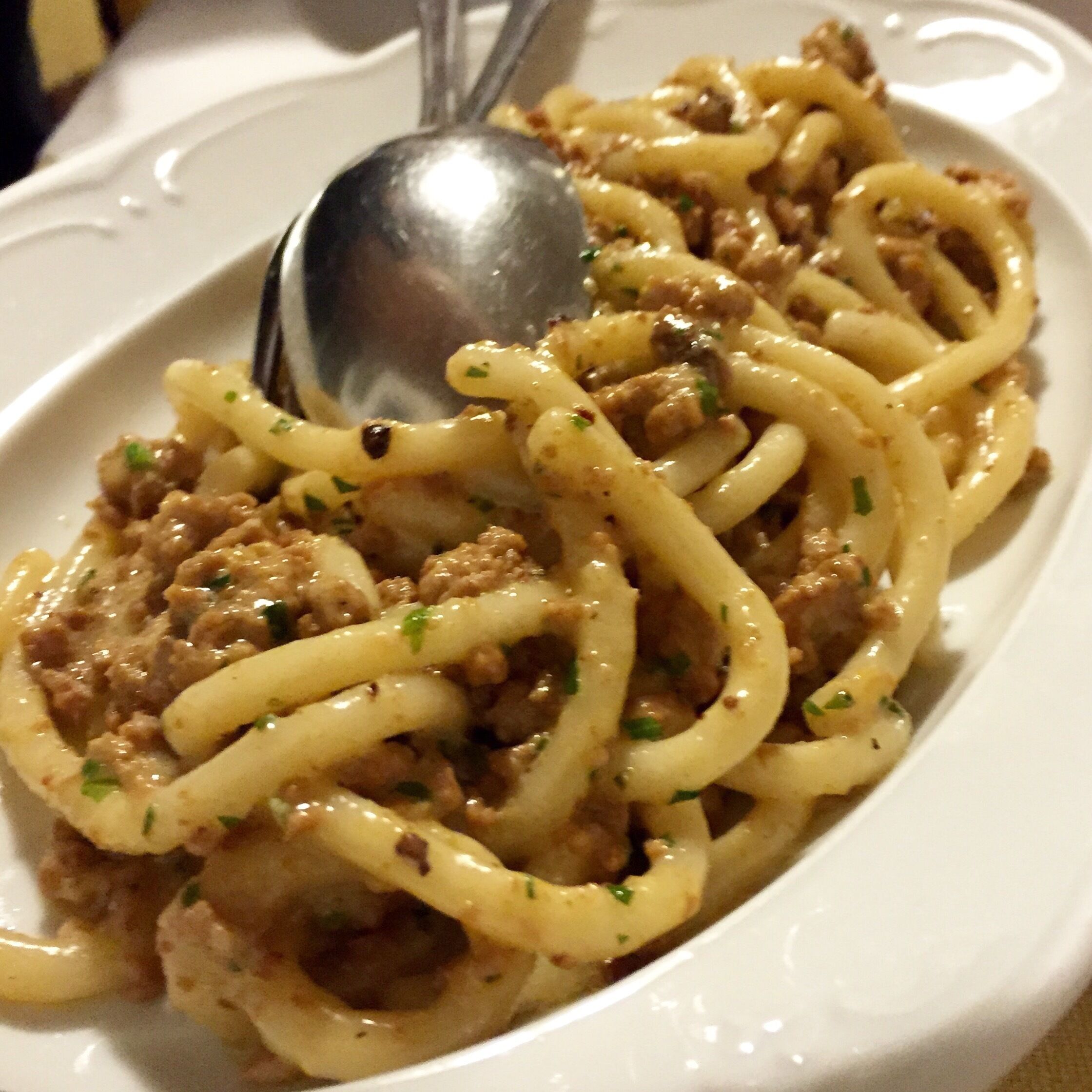 A plate of spaghetti with meat sauce and herbs.