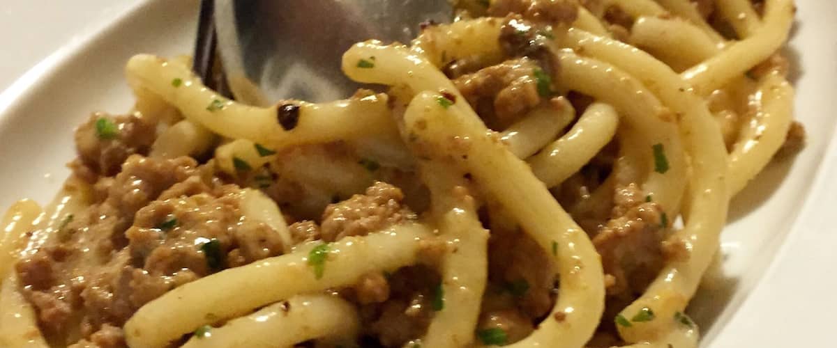 A plate of spaghetti with meat sauce and herbs.