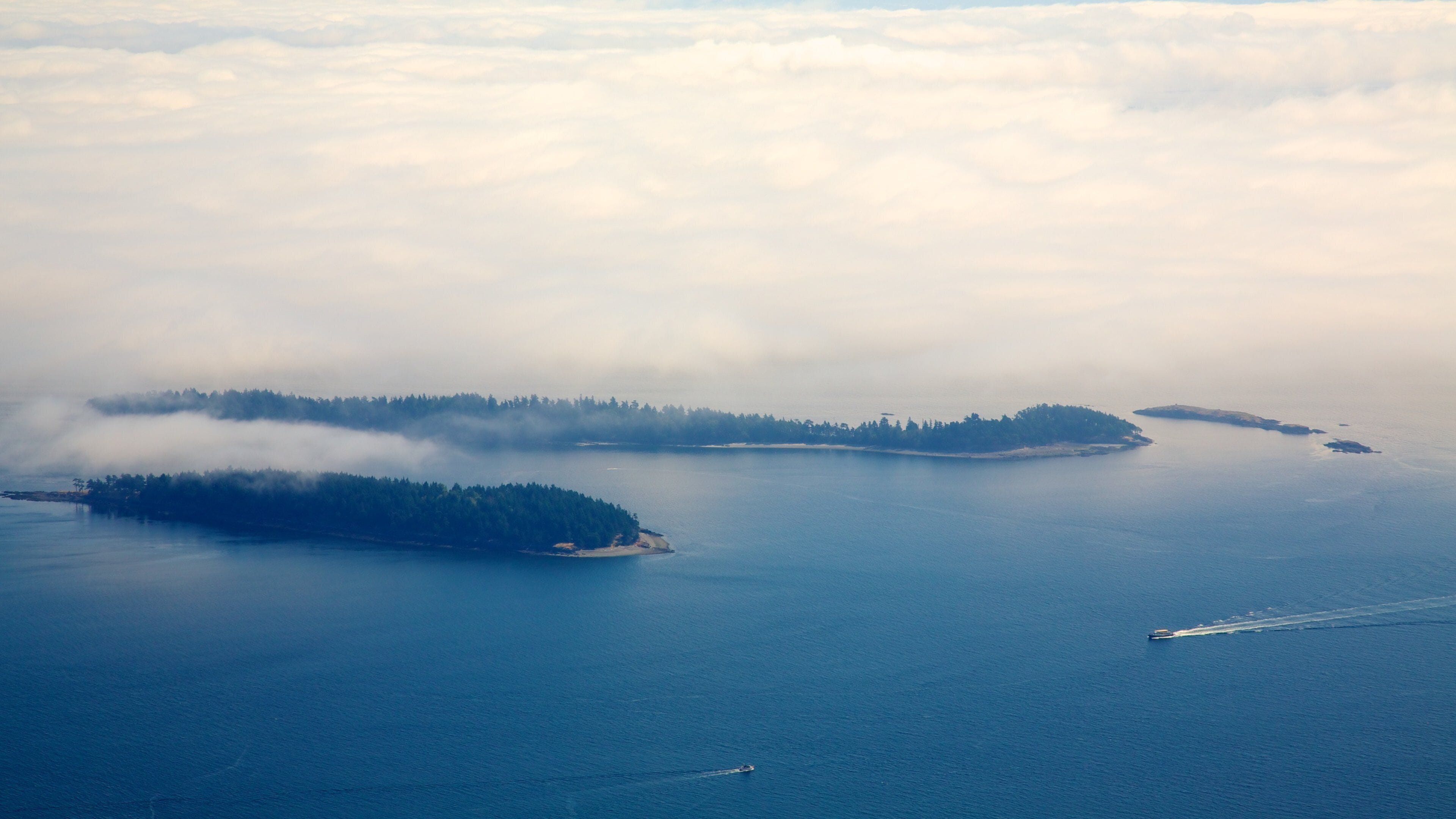 An aerial view of a coastal area with three islands surrounded by calm blue waters.