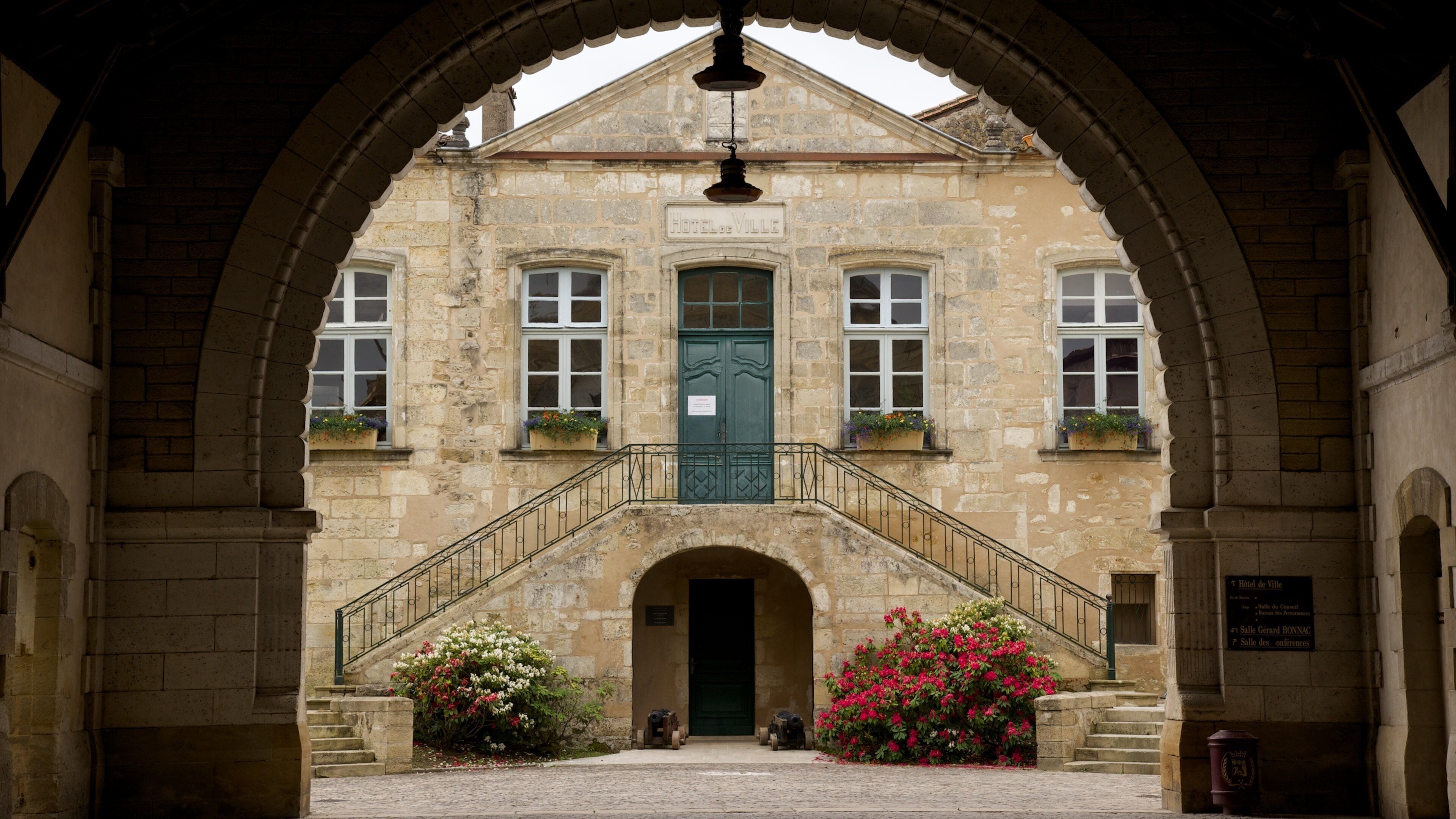 A historic building with a green door, arched windows, and a staircase leading to the entrance.