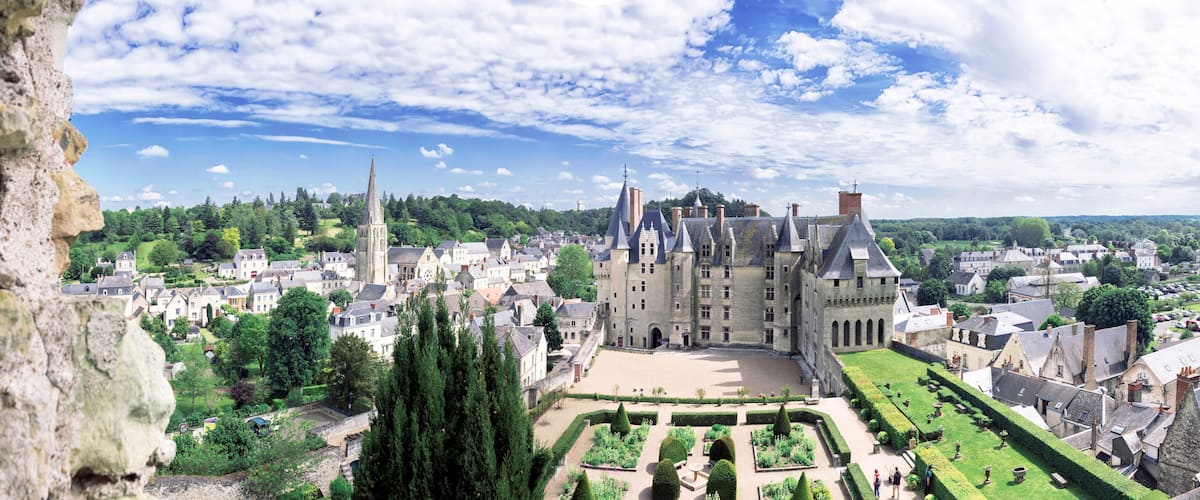 A historic castle with a large courtyard, surrounded by lush greenery and traditional architecture.