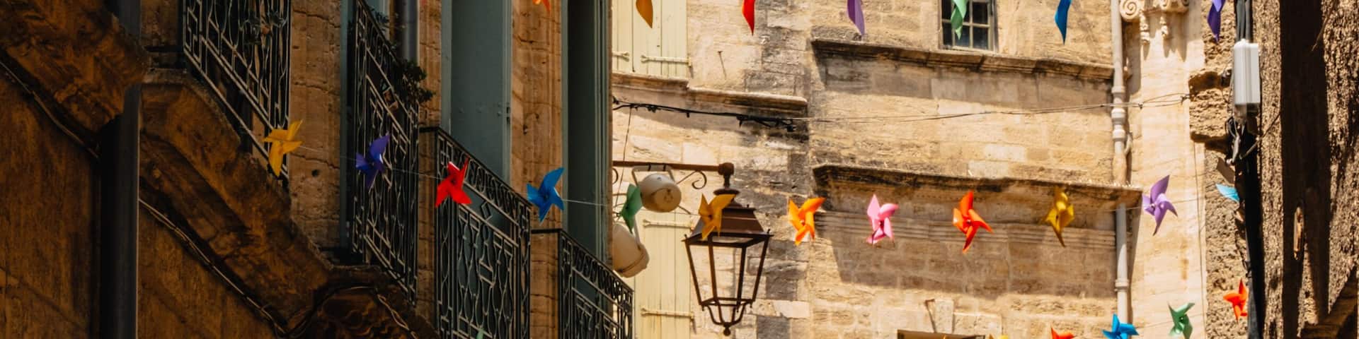 A narrow street with colorful pinwheel decorations and a historic bell tower.