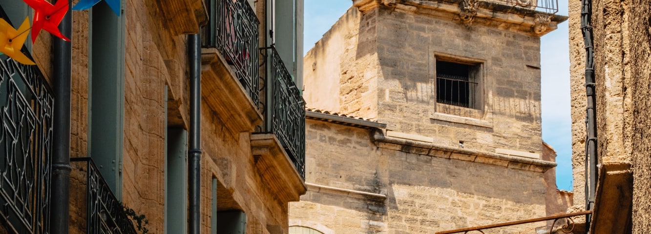 A narrow street with colorful pinwheel decorations and a historic bell tower.