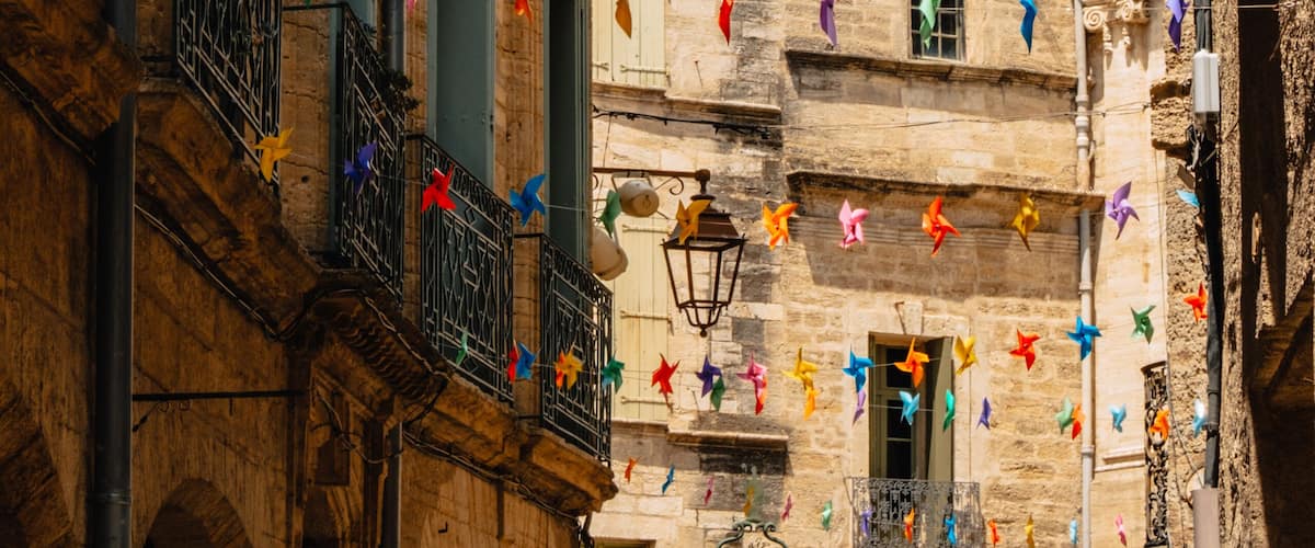 A narrow street with colorful pinwheel decorations and a historic bell tower.