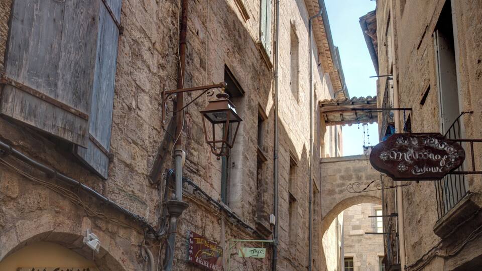 A narrow cobblestone street with old buildings, a clothing store, and a sign for 'Mecao de la Vieja'.