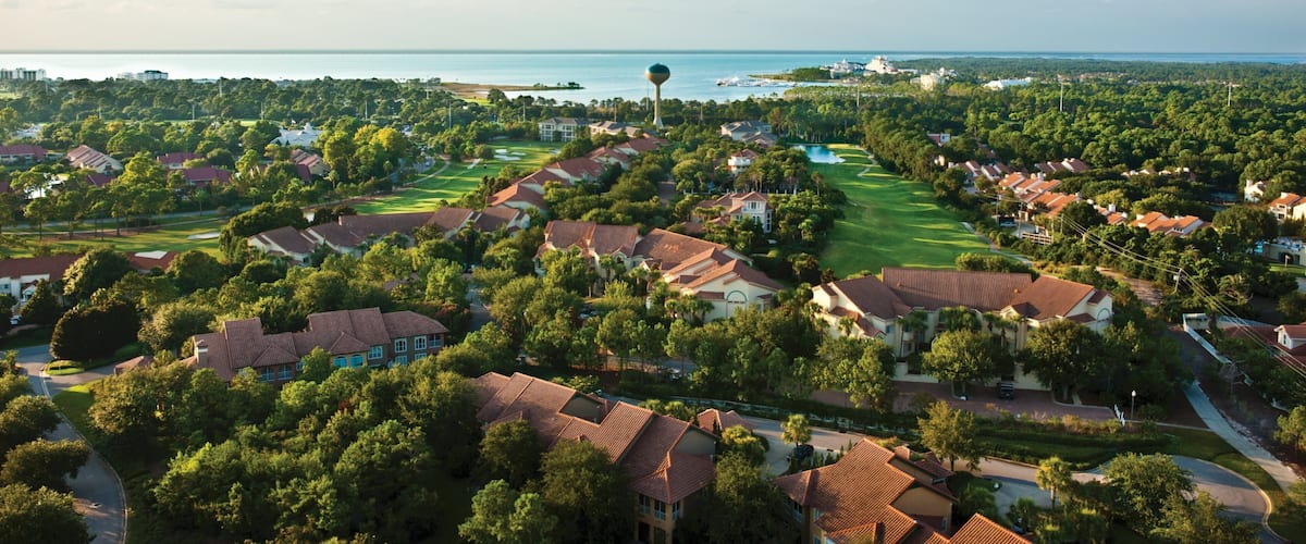 A coastal residential area with houses, a golf course, and a water tower.