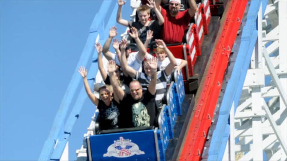 A roller coaster with passengers holding hands.