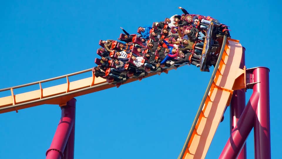 A roller coaster in motion against a clear blue sky.