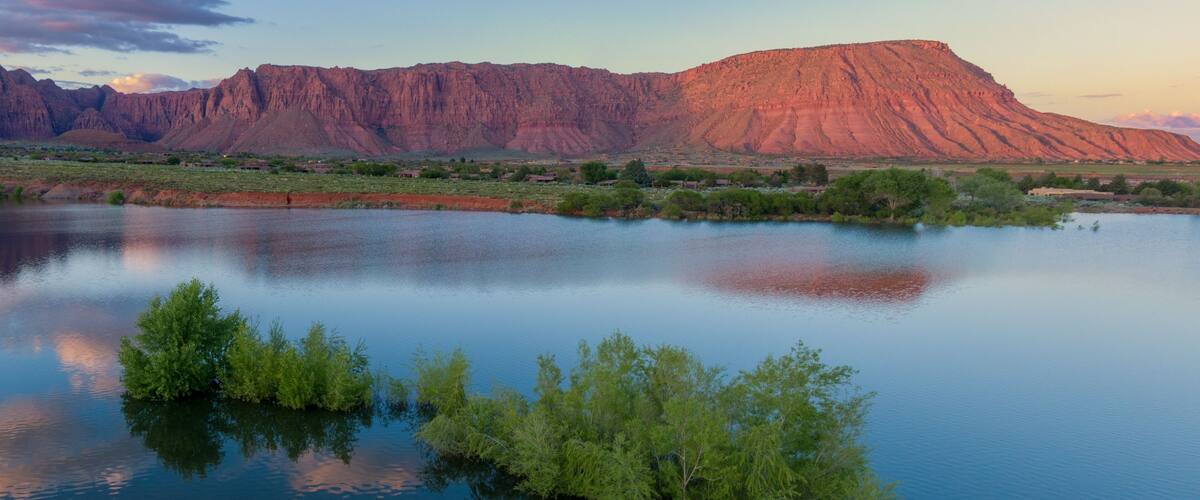 Ein ruhiger See mit einer markanten roten Felsformation im Hintergrund.