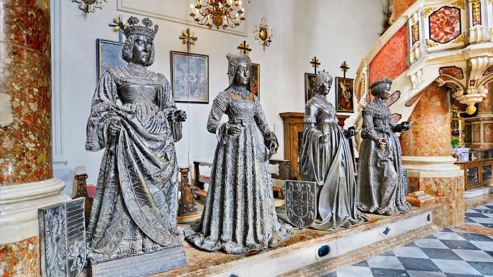 A series of statues in a grand hall with marble floors and ornate decorations.