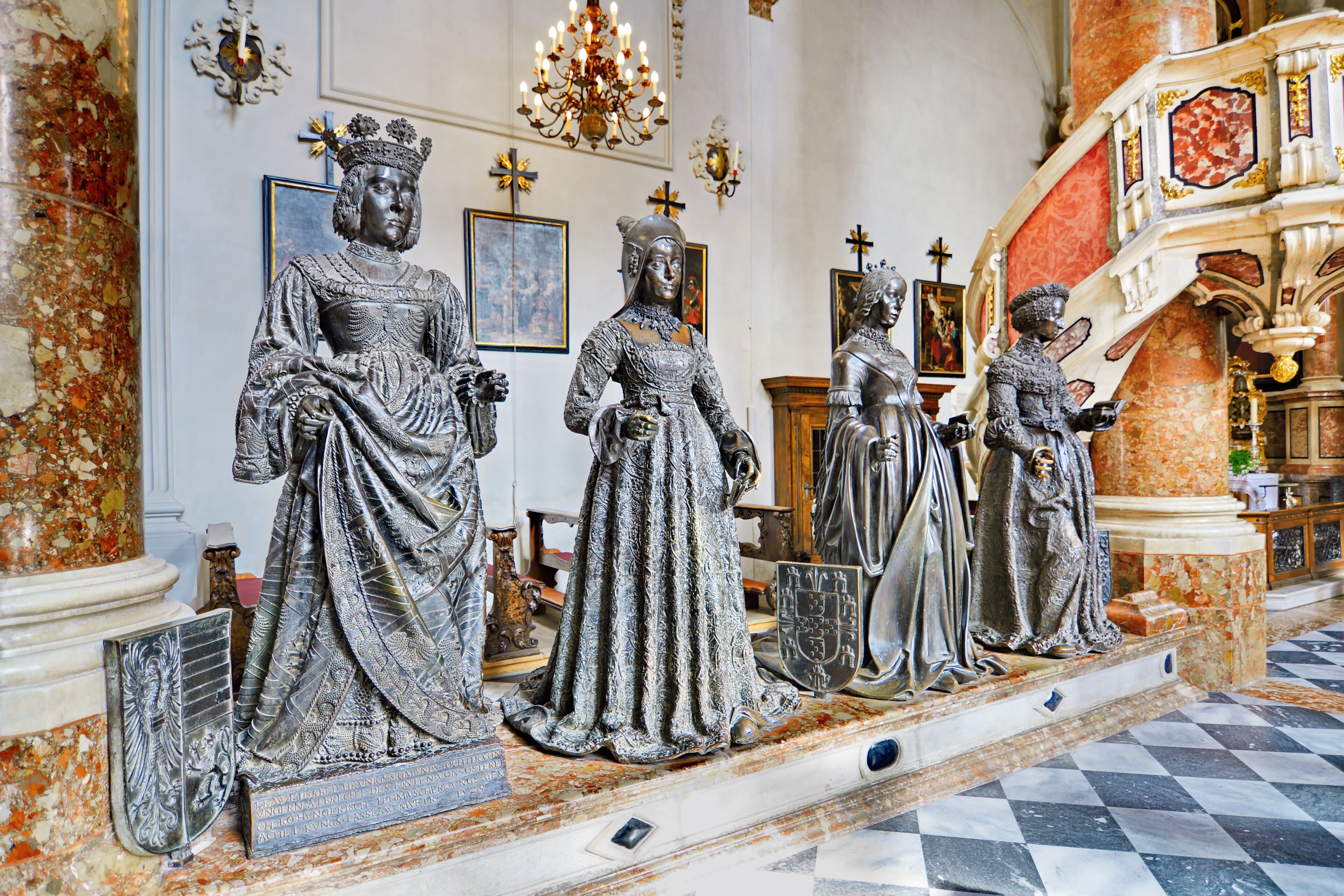 A series of statues in a grand hall with marble floors and ornate decorations.