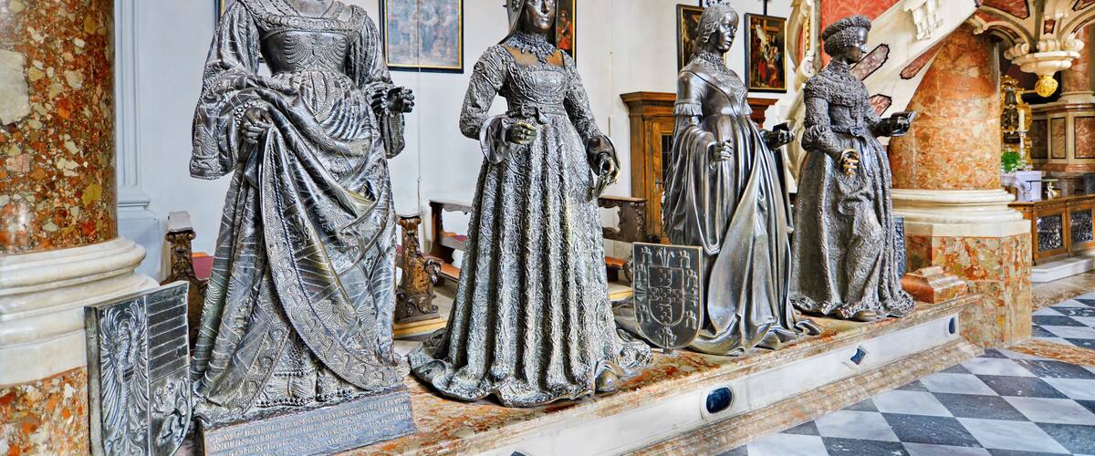 A series of statues in a grand hall with marble floors and ornate decorations.